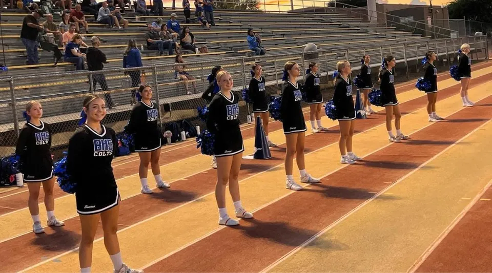 Un gruppo di cheerleader del Sierra Vista Unified School District in formazione su un campo da basket con spettatori sullo sfondo.