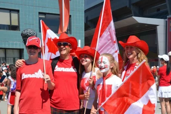 Grupo de personas vestidas de rojo celebrando con banderas de Canadá y sombreros