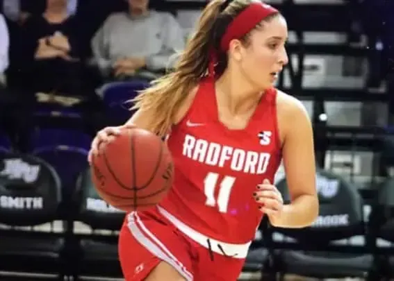 Jugadora de baloncesto con camiseta roja de Radford botando un balón en una cancha
