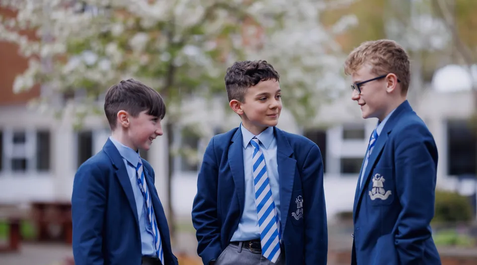 Tre studenti in divisa scolastica sono insieme nell'area esterna del St. Colmans College.