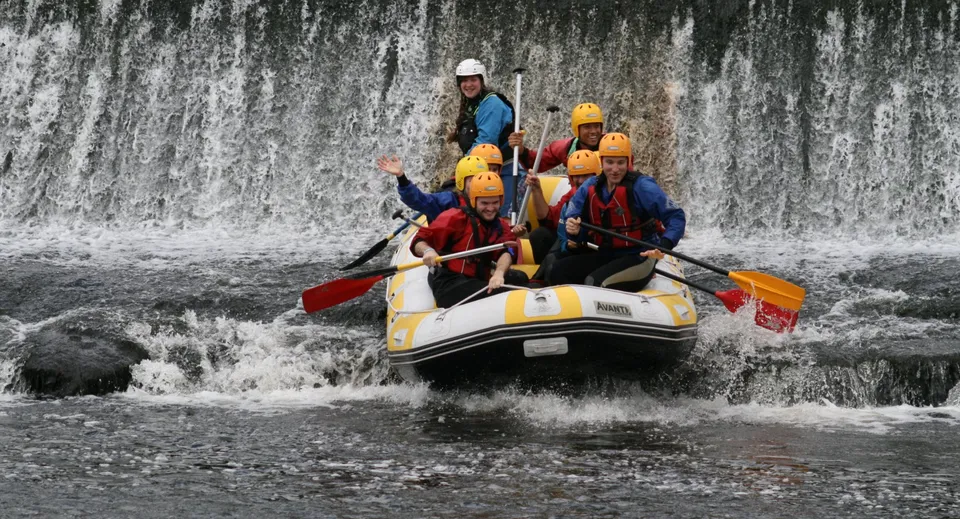 Studenti del Colaiste Chiarain Athlone passano accanto a una cascata a bordo di un gommone.