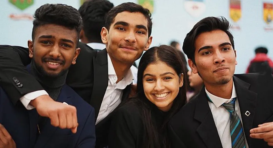 Un gruppo di studentesse e studenti del Woburn Collegiate Institute posa in abbigliamento formale davanti a uno sfondo colorato.