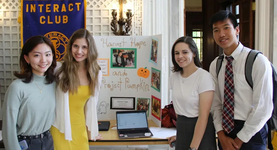 Quattro studenti sono davanti alla bacheca dell'Interact Club sul campus della Lake Forest Academy.