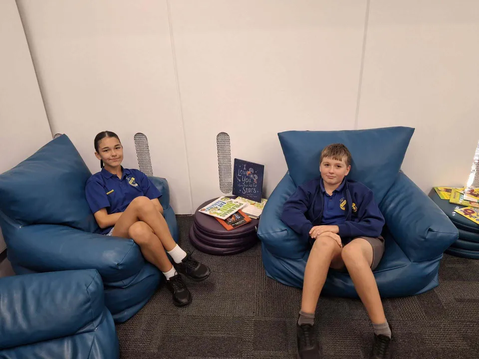 Due studenti con l'uniforme del Georges River College seduti su poltrone blu.