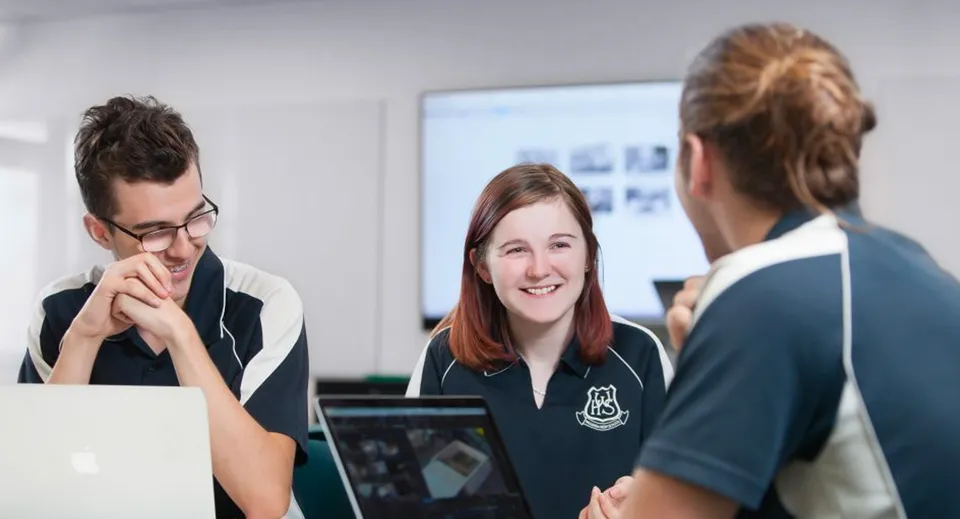 Tre persone conversano in un ambiente accademico nel campus della Willunga High School.