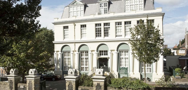 L'edificio storico della Brighton Girls School con finestre ad arco e una facciata decorativa circondata da alberi.