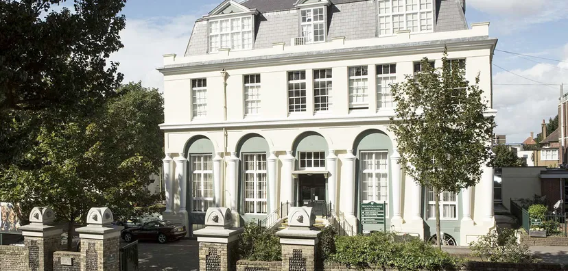 L'edificio storico della Brighton Girls School con finestre ad arco e una facciata decorativa circondata da alberi.