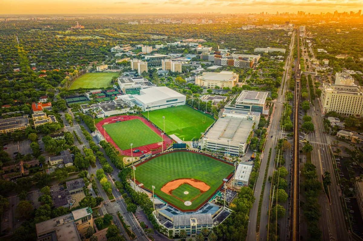 Vista aérea de un campus universitario con sus campos deportivos, palmeras y edificios