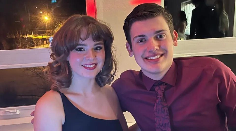 Due studenti sorridenti della Marymount Academy posano insieme in un ristorante con vista sulla città di notte.