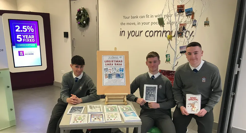 Tre studenti in uniforme si trovano dietro un tavolo da esposizione con diversi oggetti nel campus della St. Joseph's Secondary School.