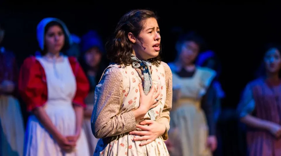 Una studentessa della Forest Ridge School of the Sacred Heart recita sul palco in abiti di scena durante uno spettacolo teatrale.
