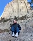 Schülerin sitzend vor einem Felsen