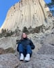 Schülerin sitzend vor einem Felsen
