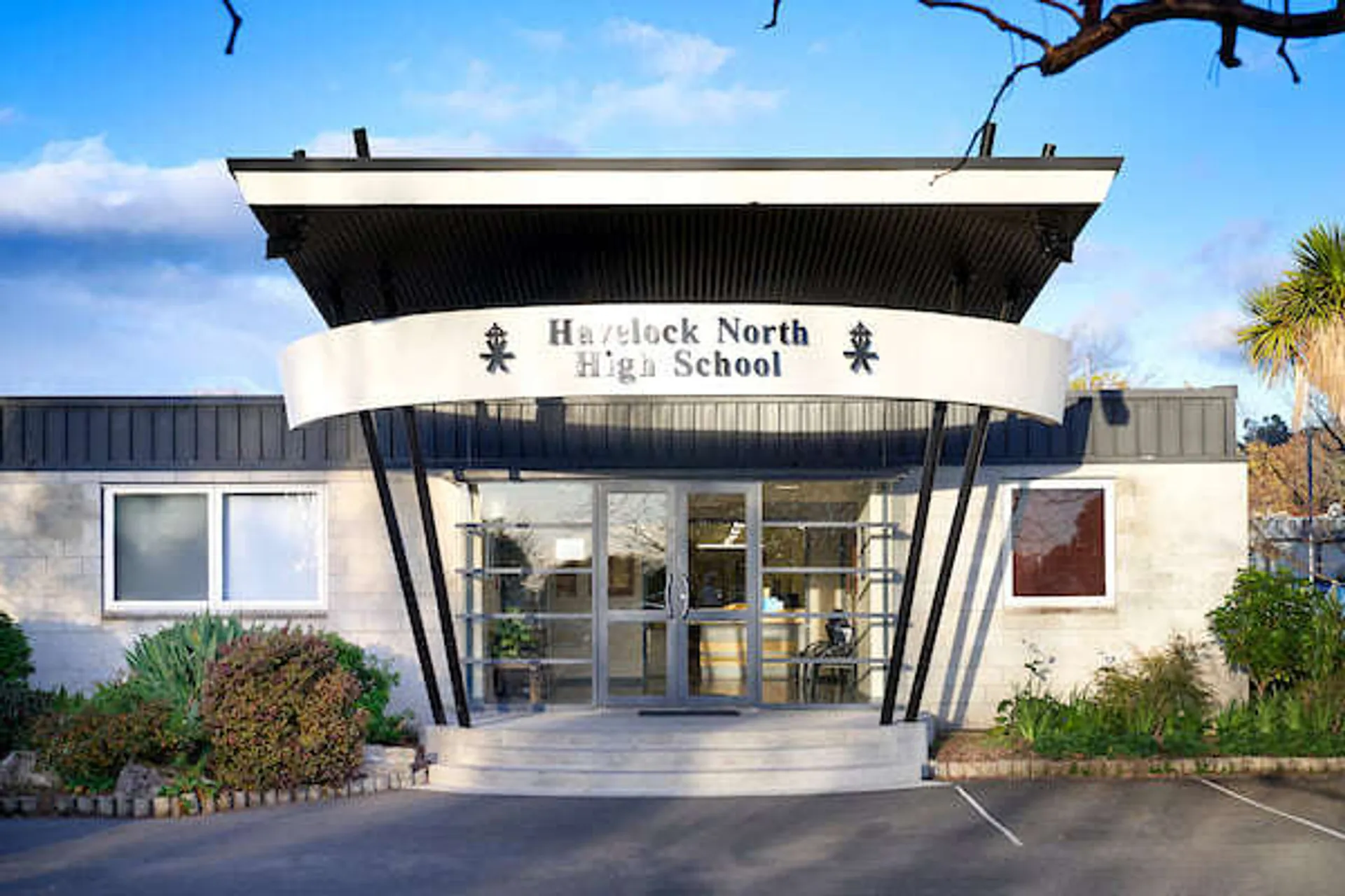 L'ingresso principale moderno della Havelock North High School con una tettoia caratteristica e dintorni curati sotto un cielo blu.