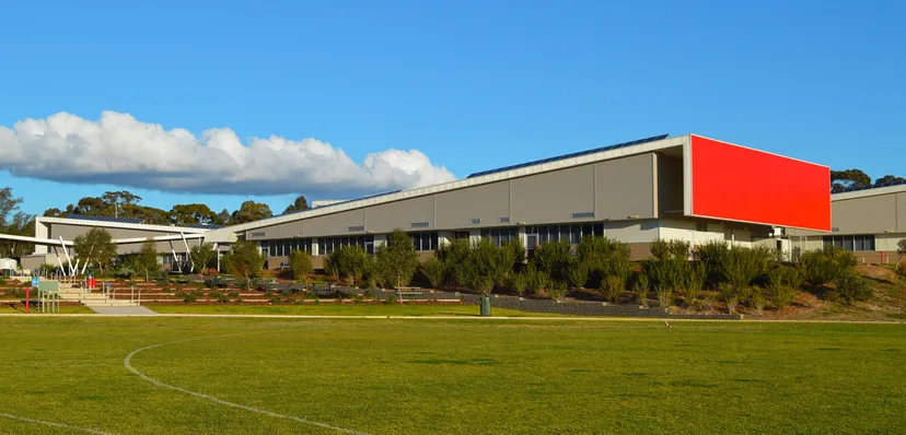 L'edificio principale moderno del Roma Mitchell Secondary College si trova davanti a un prato con alberi sotto un cielo azzurro.