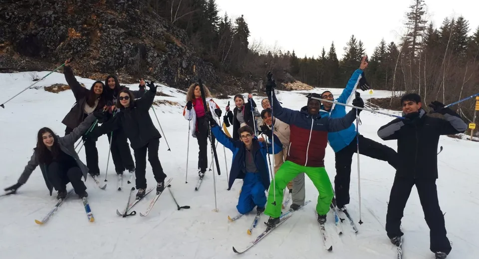 Studenti del Collège Episcopal Saint Étienne mentre sciano su un percorso innevato tra gli alberi.