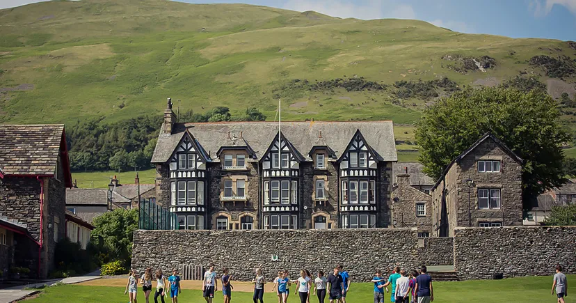 Un edificio storico in stile Tudor della Sedbergh School con colline verdi circostanti e montagne sullo sfondo.