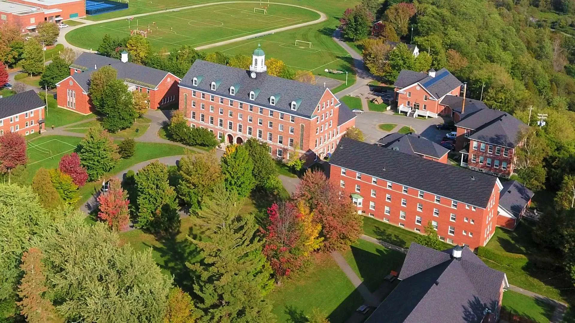 Vista aerea del campus della Sussex Christian School con edifici in mattoni rossi, alberi e campi sportivi.