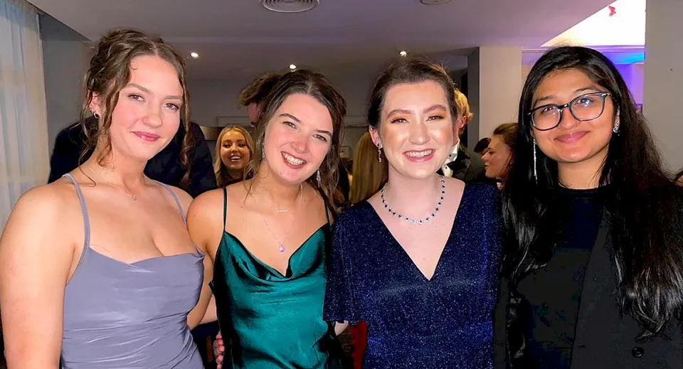 Quattro studentesse del Loreto College in abito da sera sorridono insieme verso la fotocamera.