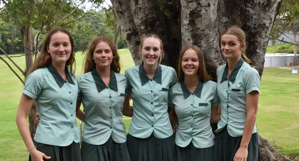 Un gruppo di cinque studentesse della Ferny Grove State High School sta davanti a un albero con una folta chioma.