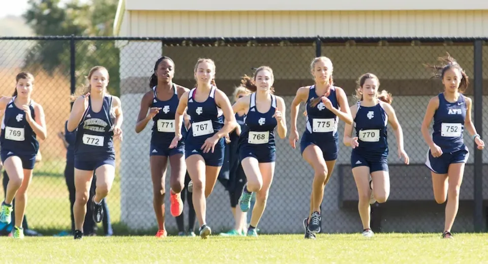 Un gruppo di atlete corre sulla pista da atletica nel terreno della Sir Guy Carleton Secondary School.