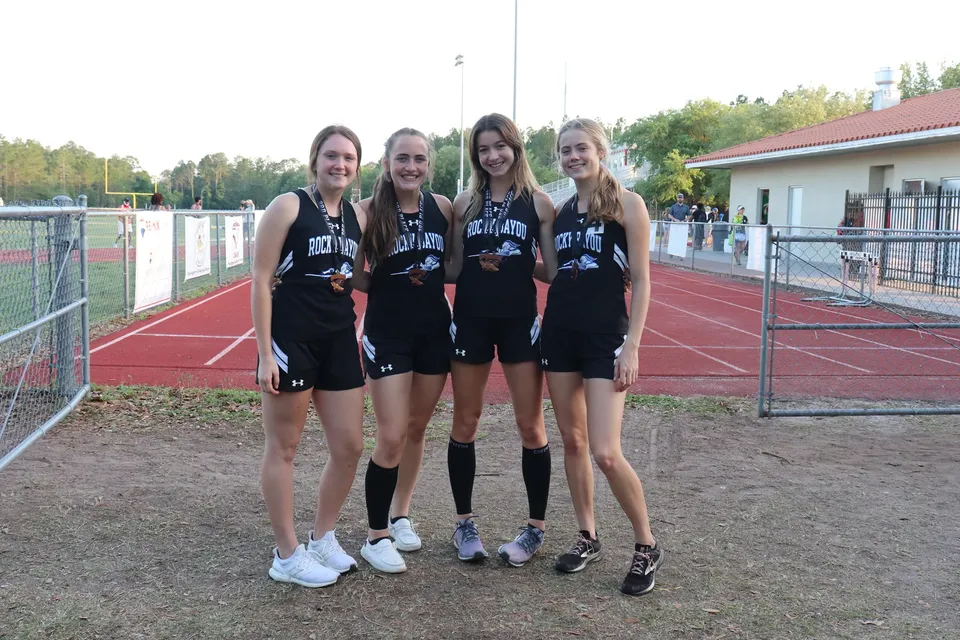 Quattro studentesse in abbigliamento sportivo stanno insieme sul campo sportivo della Rocky Bayou Christian High School.