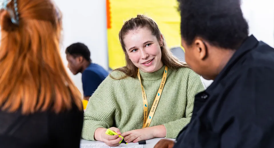 Una donna con un maglione verde parla con due persone nel campus della The Wren School.