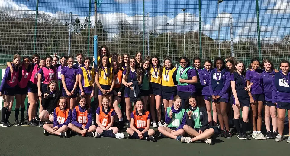 Un grande gruppo di giovani studentesse in divise sportive colorate sul campo sportivo della LVS Ascot.