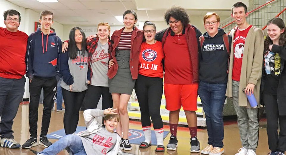 Un gruppo di studenti e studentesse nell'area comune della D.W. Poppy Secondary School.
