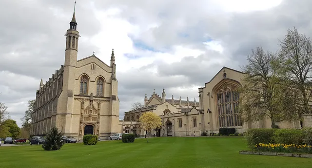 Eine prächtige gotische Kathedrale mit hohem Turm steht im grünen Innenhof des Cheltenham College unter bewölktem Himmel.