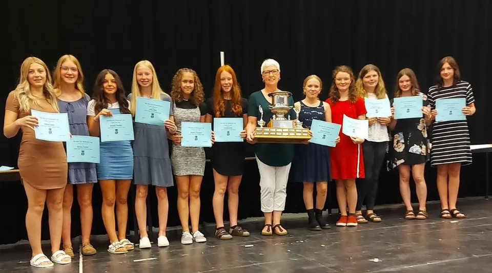 Studentesse della Indian River High sono insieme sul palco e tengono in mano attestati e una coppa.