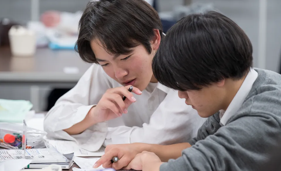 Zwei Schüler der Hinodegakuen Senior High School sitzen an einem Tisch und lernen gemeinsam mit ihren Unterlagen.