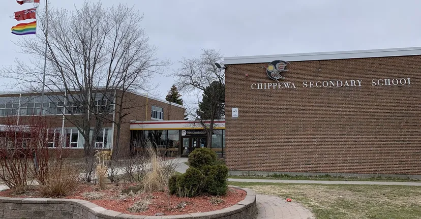 L'edificio in mattoni della Chippewa Secondary School con la facciata scritta circondato da alberi spogli e un prato.