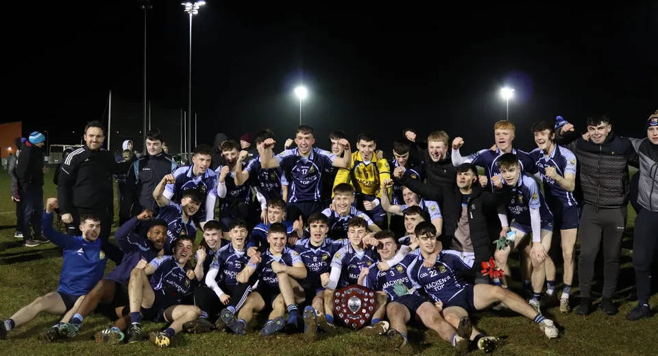 La squadra sportiva della Cnoc Mhuire Secondary School posa insieme sul campo sportivo di notte.