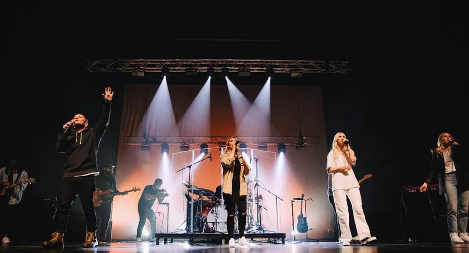 Un gruppo di studenti della Centennial Secondary School si esibisce su un palco ben illuminato.