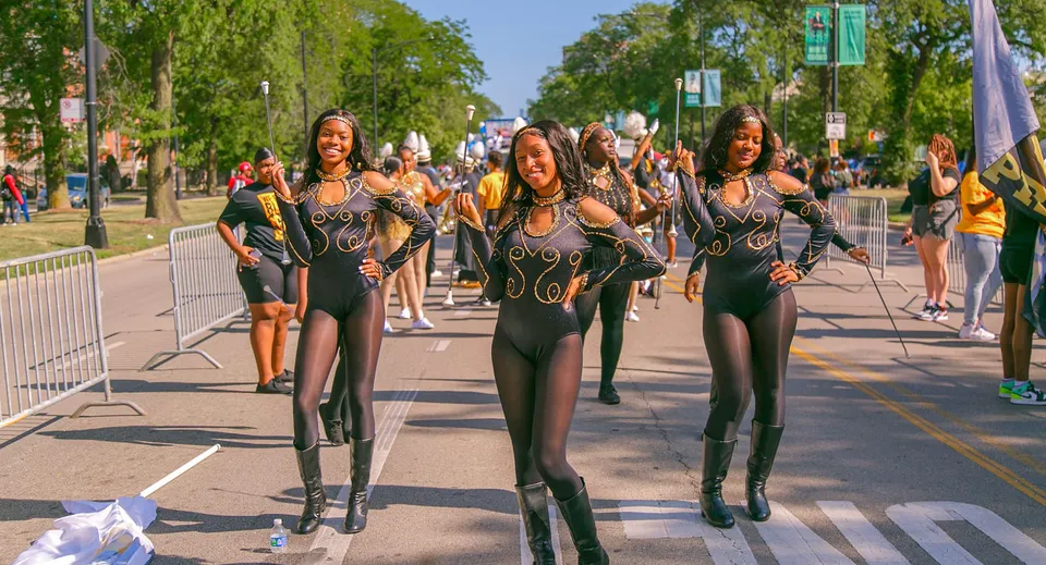 Un gruppo di donne con outfit neri e aderenti cammina lungo una strada, scattata nei pressi delle Chicago Public Schools.