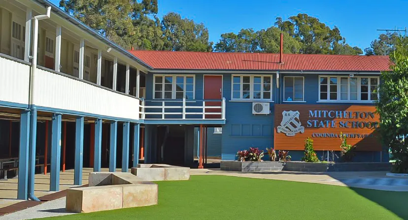 L'edificio scolastico della Mitchelton State High School con il tetto rosso, circondato da alberi e da un prato.
