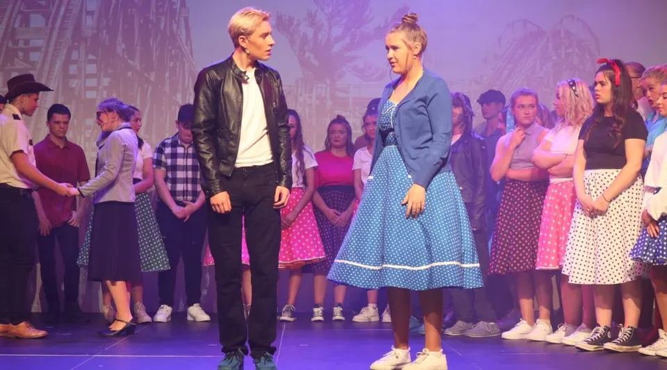 Un uomo e una donna si trovano sul palco davanti a un gruppo di persone nel campus della St Ailbe's School.