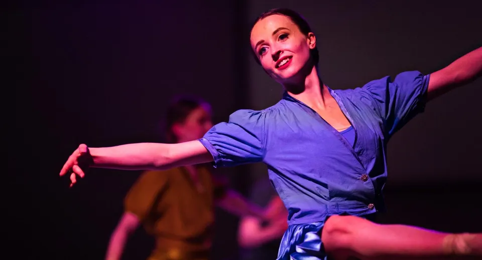 Una donna in abiti blu danza sul palco della Scoil Ruáin.