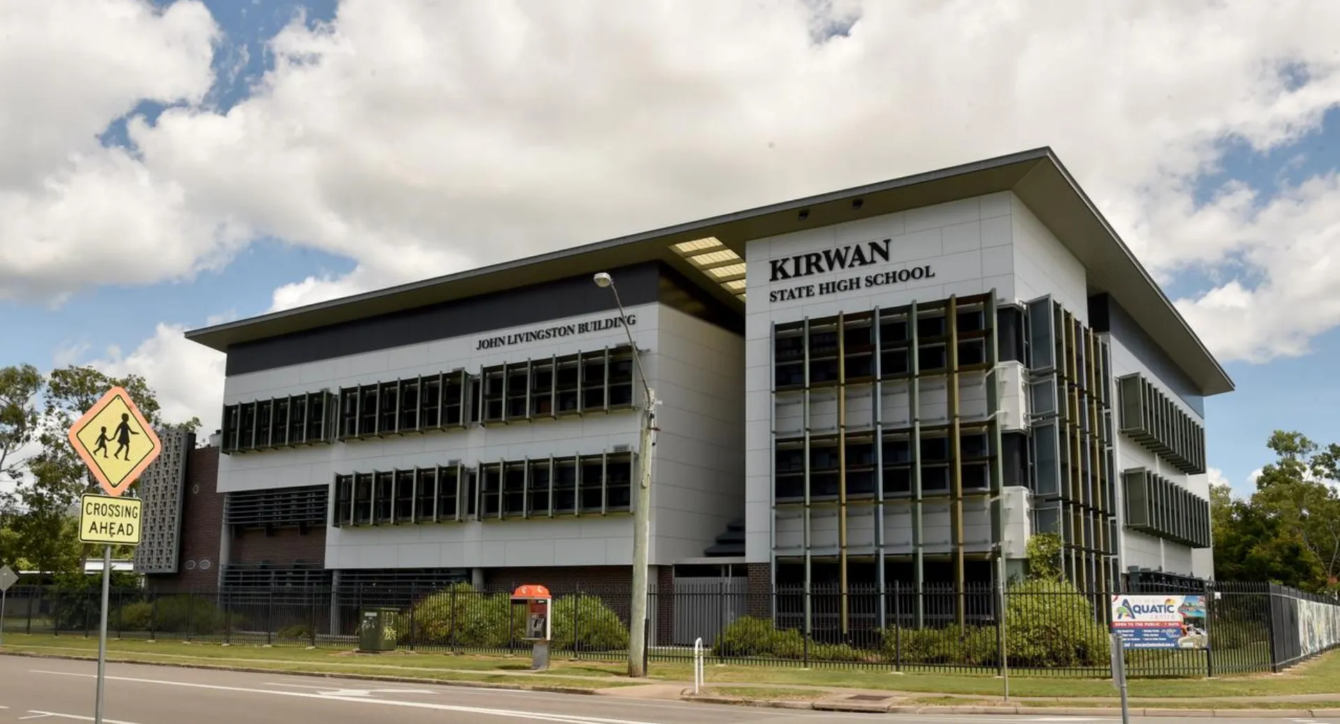 L'edificio a più piani con la scritta Kirwan State High School è circondato da alberi e da una strada.