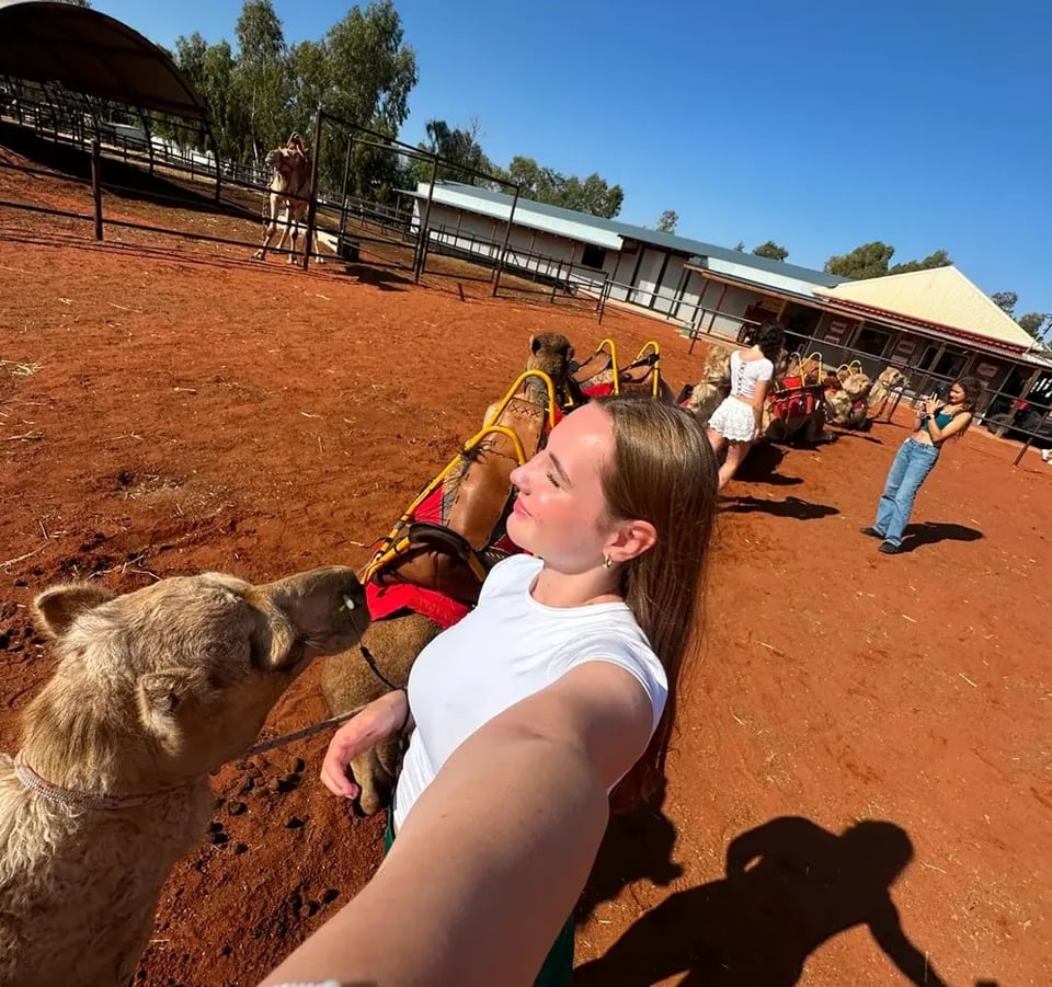 Alicia macht ein Selfie neben Kamelen auf einer Farm im australischen Hinterland