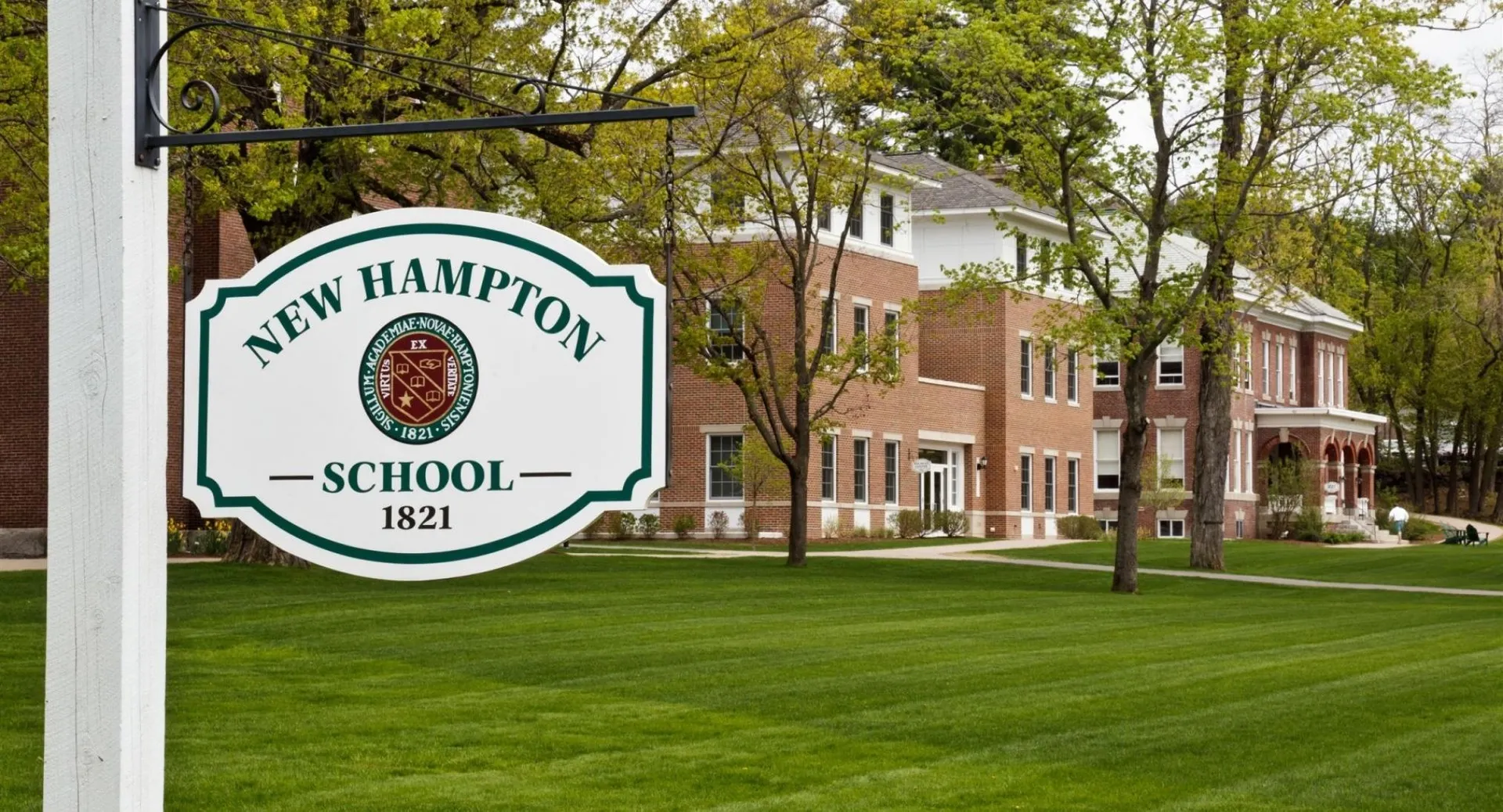 L'edificio in mattoni della New Hampton School è circondato da alberi verdi e da un prato ben curato.