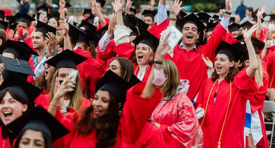 Un gruppo di diplomati e diplomate della Robina State High School festeggia il proprio diploma in toge e tocchi rossi.