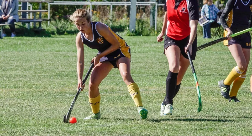 Una giocatrice di hockey su prato della St. John’s-Kilmarnock School controlla la palla sul campo.