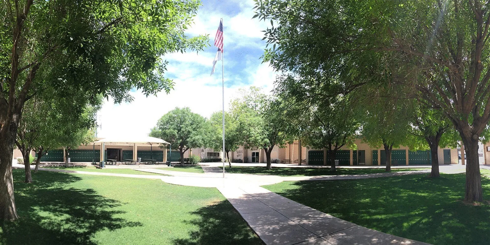 Il campus della Phoenix Christian Preparatory School mostra un viale alberato con un edificio e la bandiera americana.