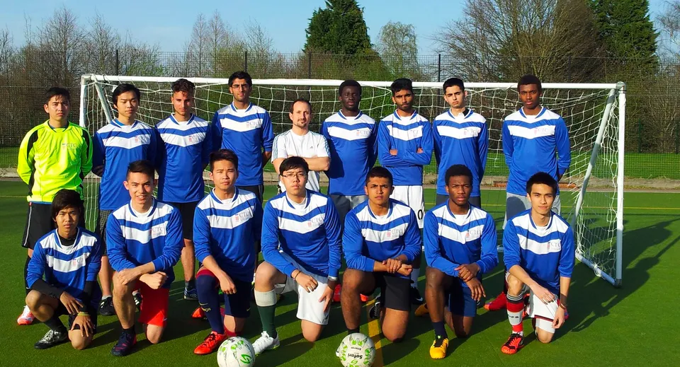 Un gruppo di studenti del Cambridge Tutors College davanti a una porta da calcio su un campo in erba.