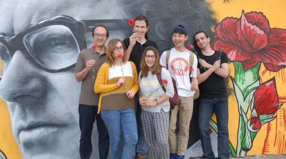 Un gruppo di giovani adulti sta davanti a un murale floreale colorato nel campus del Greene's College Oxford.