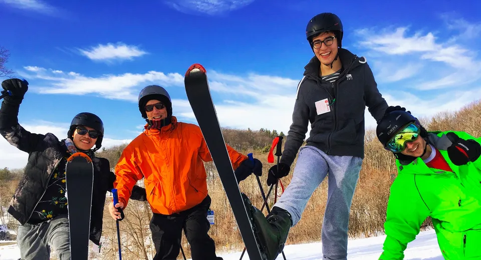 Un gruppo di studenti della Ross School si trova su un campo innevato in abiti invernali sotto un cielo limpido.