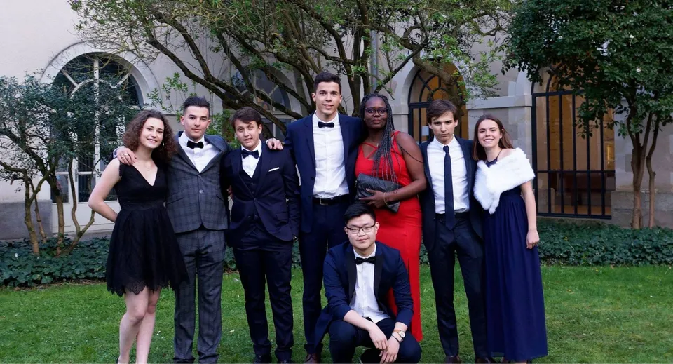 Un gruppo di persone posa in abbigliamento formale davanti a uno sfondo ricco di alberi all'interno della Institution Mongazon.
