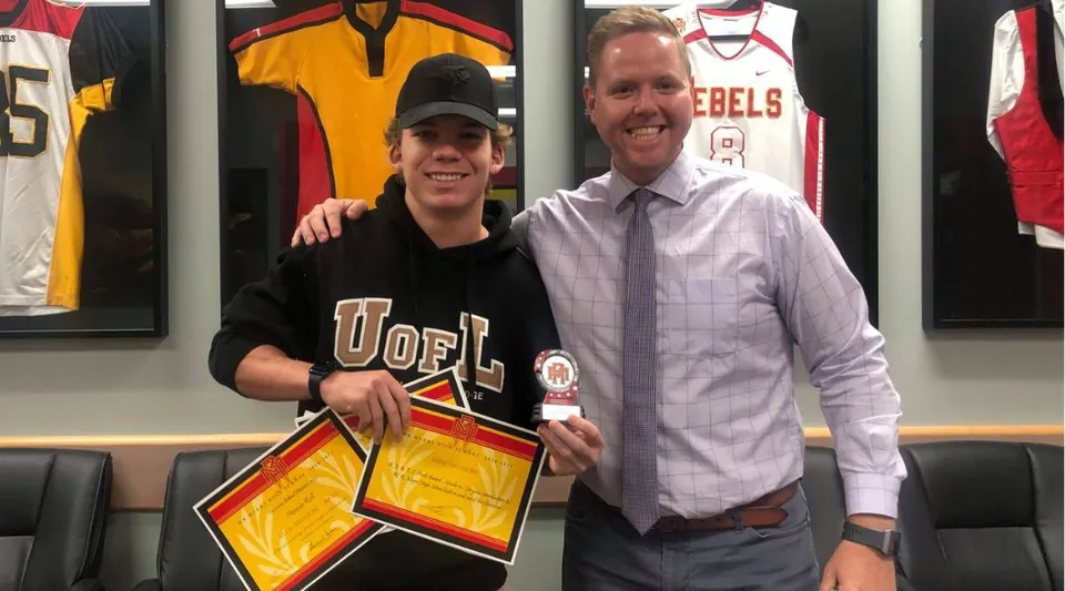 Un uomo e una donna si trovano in un ambiente sportivo con maglie da gioco sullo sfondo nel campus della W.R Myers High School.